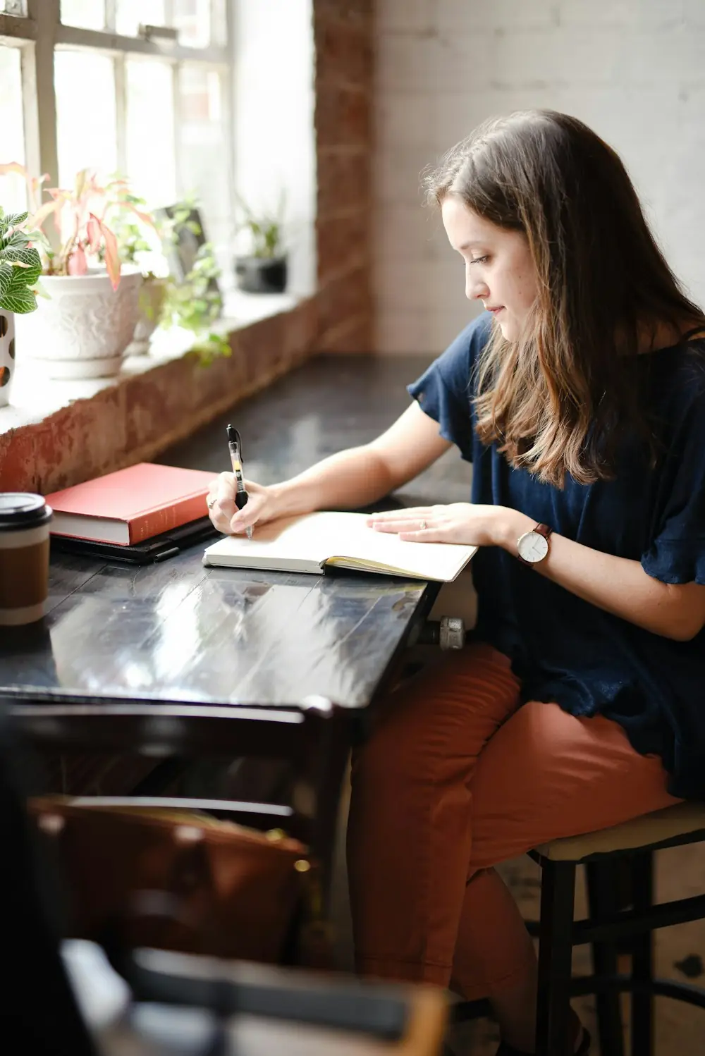 Persona escribiendo en un cuaderno junto a una ventana